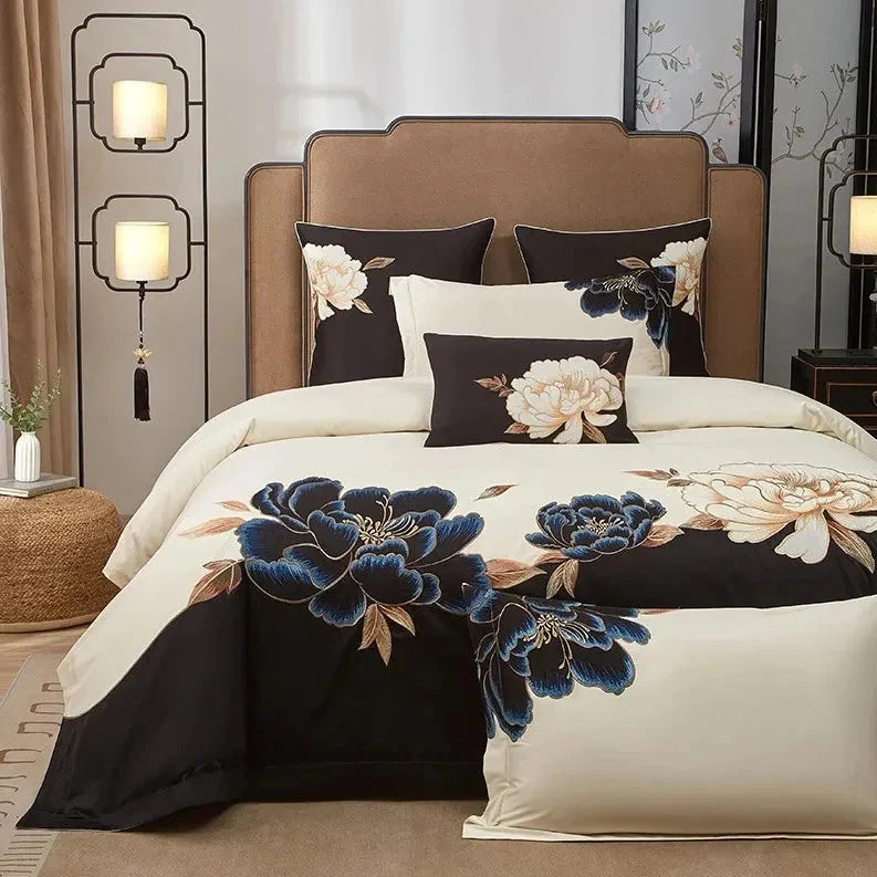 Blue floral embroidery on a black and ivory duvet cover creates a bold botanical focal point on an elegantly styled bed – L&B