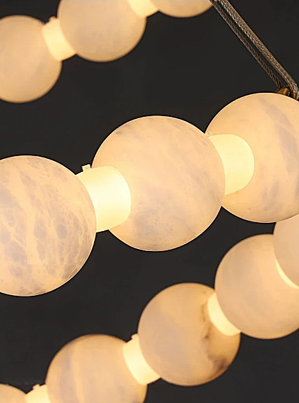 Alabaster stone orb chandelier glowing warm light through natural veining – organic modern luxury pendant light detail 