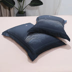Stacked navy blue pillow shams featuring subtle winter forest and tree branch patterns – L&B