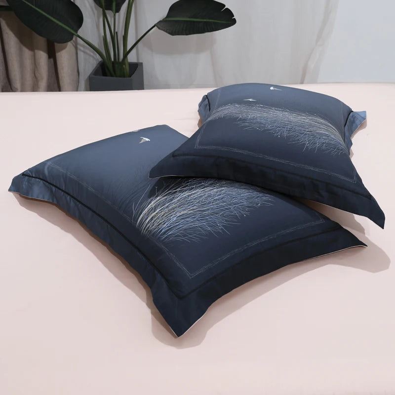 Stacked navy blue pillow shams featuring subtle winter forest and tree branch patterns – L&B