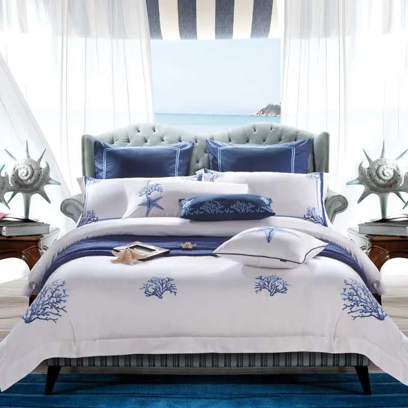 White and blue coastal duvet cover set with embroidered coral and starfish motifs in an ocean-view bedroom – L&B