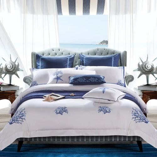 White and blue coastal duvet cover set with embroidered coral and starfish motifs in an ocean-view bedroom – L&B