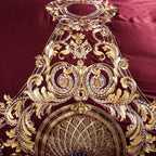 Close-up of ornate gold baroque medallion embroidery on burgundy bedding, ZUTAPERA – L&B