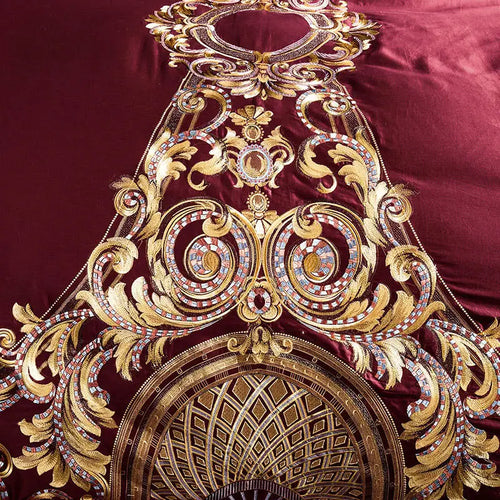 Close-up of ornate gold baroque medallion embroidery on burgundy bedding, ZUTAPERA – L&B