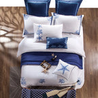 White and navy blue Egyptian cotton bedding styled in a bright coastal bedroom with ocean views – L&B