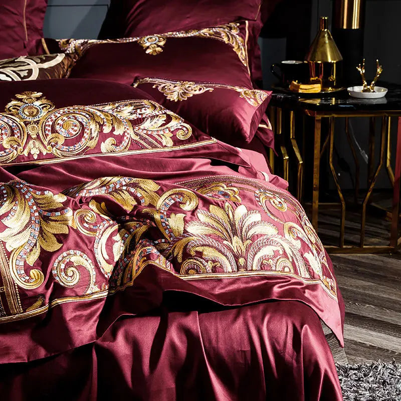 Layered burgundy and gold embroidered bedding shown from an elegant bedside view, ZUTAPERA – L&B