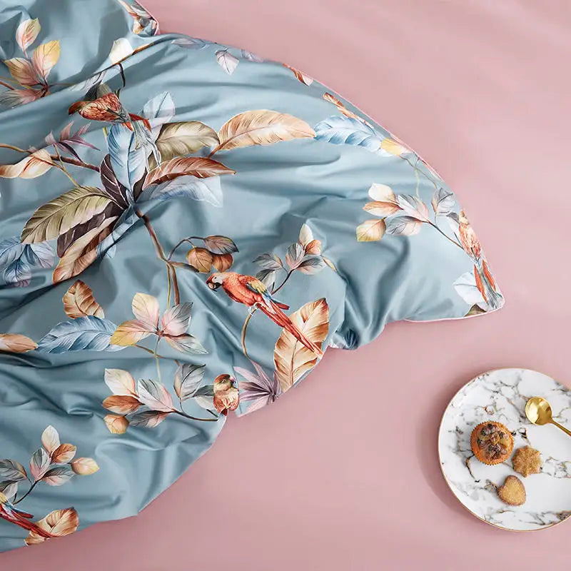 Tropical parrot duvet cover draped across blush pink bedding with botanical bird artwork – L&B