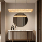 Alabaster linear chandelier with a gold canopy above a modern entryway console and round wall mirror