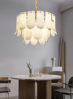 Tiered alabaster chandelier above a round dining table in a contemporary neutral interior - L&B