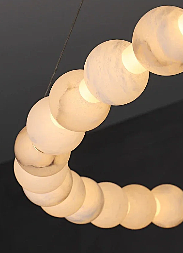 Natural alabaster bead ring arc close-up showing warm honey glow through stone – luxury chandelier detail