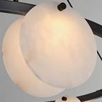 Close-up of a glowing natural alabaster disc on a sculptural chandelier - L&B