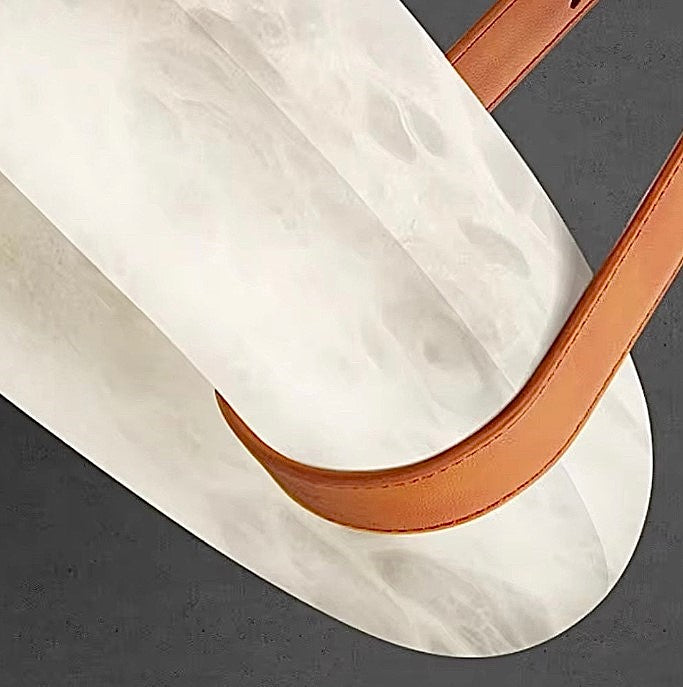 Close-up of a natural alabaster ring pendant light with a warm brown leather suspension strap - L&B