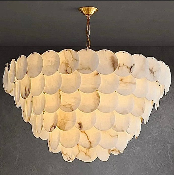 Tiered alabaster disc chandelier with a brass chain and warm glow against a dark wall - L&B