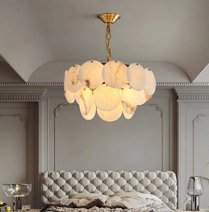 Alabaster disc chandelier above an upholstered bed in a modern luxury bedroom - L&B