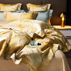Gold jacquard duvet cover set with fluid marble detailing, layered blue-gray pillows, and a luminous satin finish – L&B