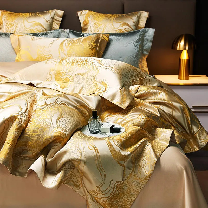 Gold jacquard duvet cover set with fluid marble detailing, layered blue-gray pillows, and a luminous satin finish – L&B