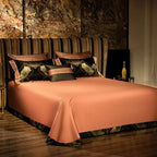 Solid copper-toned flat sheet with a smooth satin finish and coordinating black decorative pillows – ROYAL H. BLACK – L&B