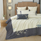 Luxury ivory floral bedding styled with blue leaf embroidery, gray accents, and coordinating decorative pillows – L&B