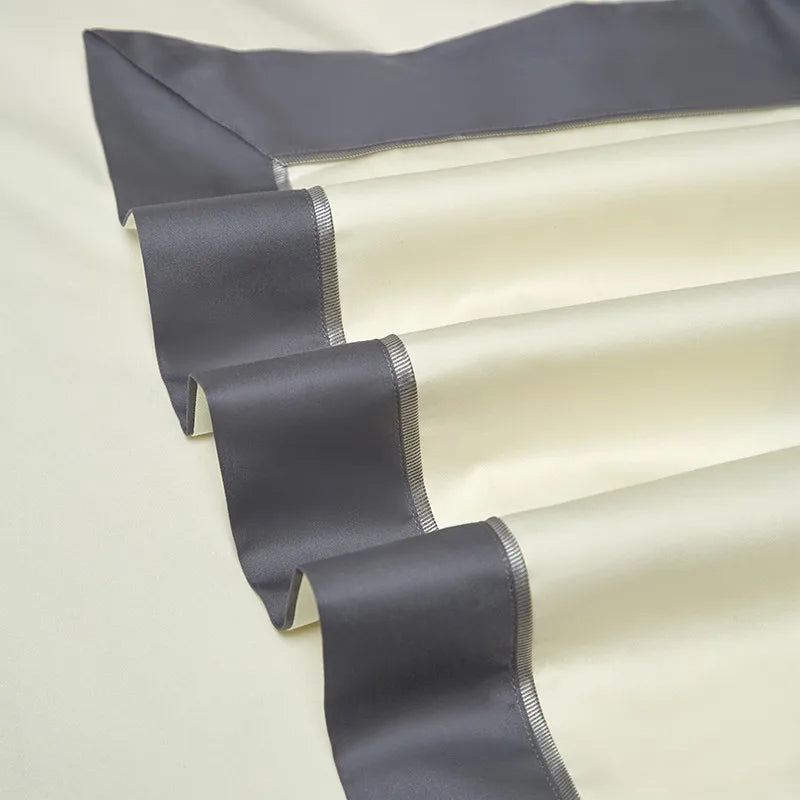 Folded ivory Egyptian cotton bedding with a wide gray border and clean tailored detailing – L&B