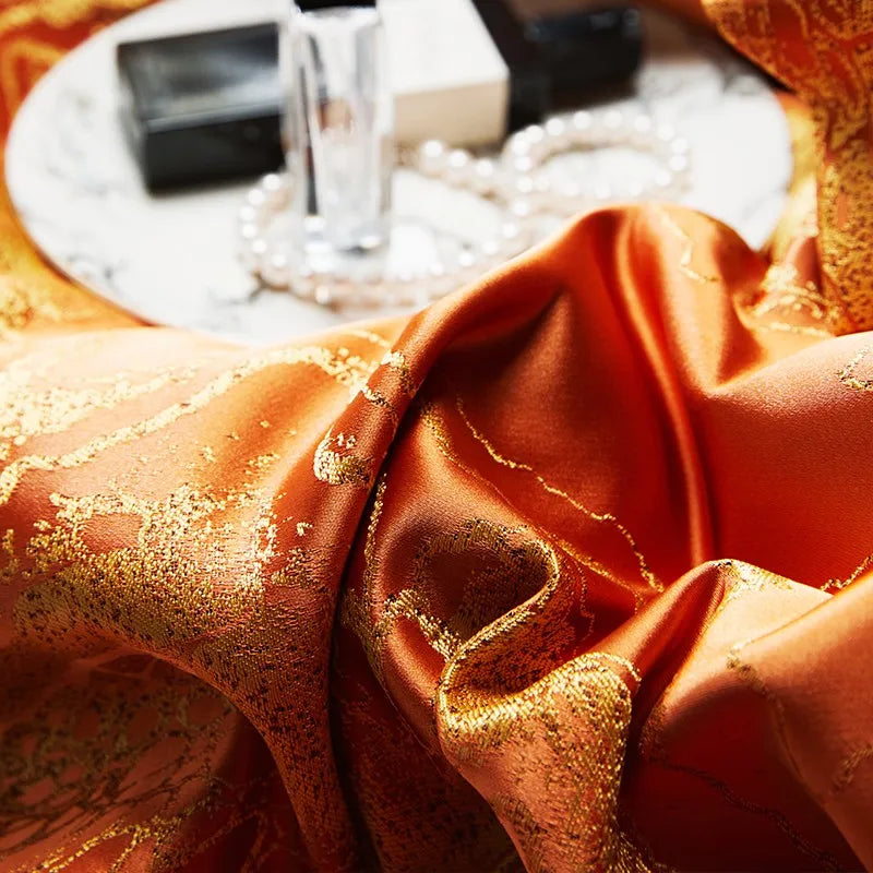 Macro close-up of orange jacquard duvet fabric with an intricate damask weave and rich lustrous texture – L&B