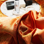Macro close-up of orange jacquard duvet fabric with an intricate damask weave and rich lustrous texture – L&B