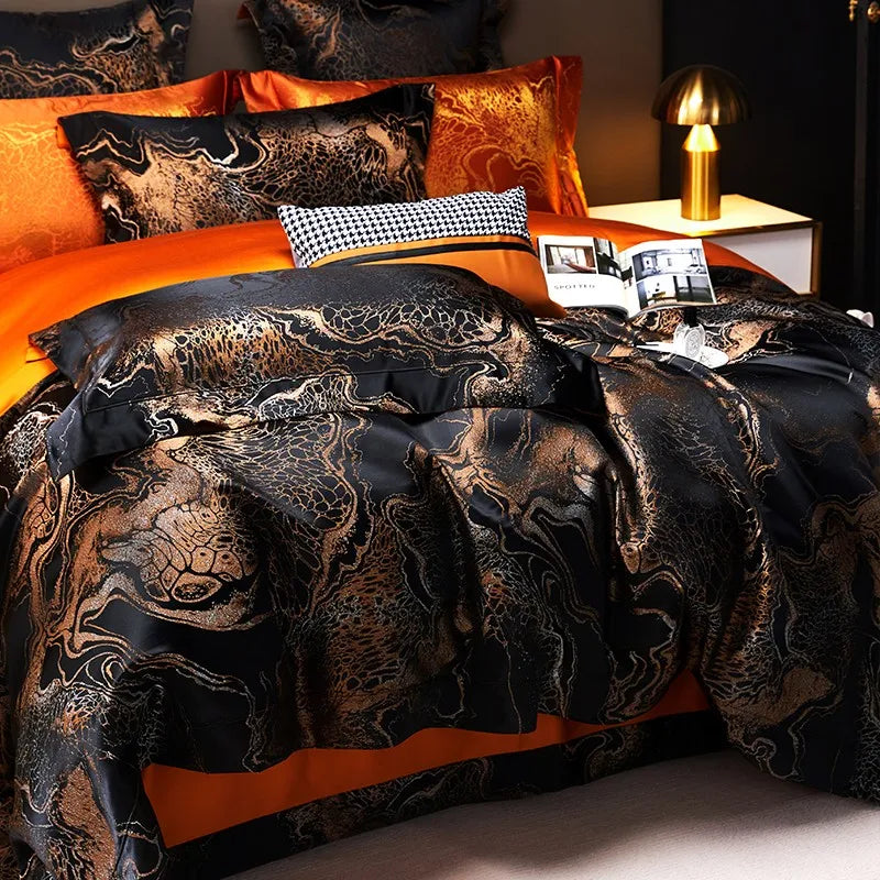 Luxury black and gold bedding set styled with an ornate jacquard duvet cover, orange pillows, and a gray accent cushion – L&B