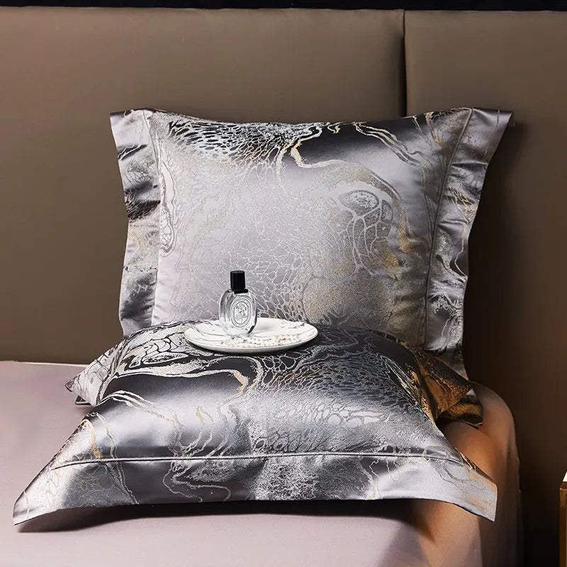 Charcoal gray jacquard pillow sham and folded duvet cover displayed with intricate platinum detailing – L&B