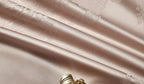 Close-up of smooth champagne beige 1200TC Egyptian cotton satin fabric with luminous folds and silky luster - L&B