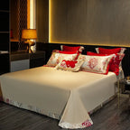 Ivory Egyptian cotton flat sheet styled with red floral embroidered pillows and a smooth satin finish – L&B