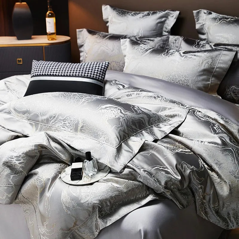 Close-up of silver gray jacquard bedding showing softly gathered folds and an intricate metallic woven pattern – L&B
