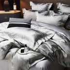 Close-up of silver gray jacquard bedding showing softly gathered folds and an intricate metallic woven pattern – L&B