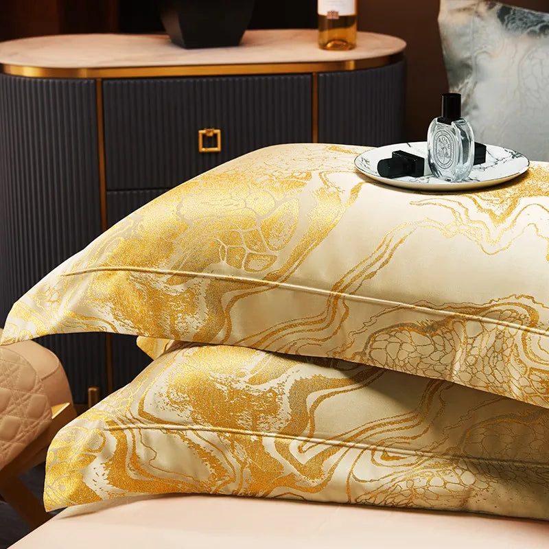 Gold marble pillow shams and folded jacquard duvet displayed in a coordinated luxury bedding arrangement – L&B