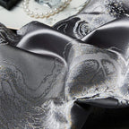 Macro view of charcoal jacquard fabric showing the dragon and cloud-inspired motif and luminous platinum finish – L&B