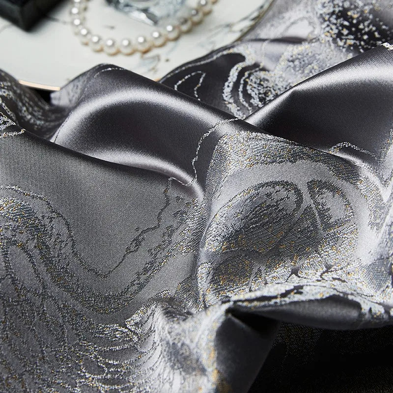 Macro view of charcoal jacquard fabric showing the dragon and cloud-inspired motif and luminous platinum finish – L&B