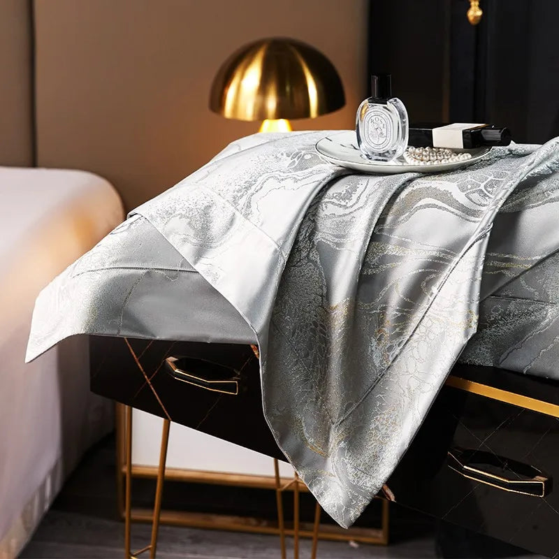 Side view of a luxury silver duvet cover draped over a contemporary bed with a fluid metallic sheen – L&B