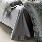 Silver jacquard duvet cover draped over a smooth gray Egyptian cotton sheet with a tailored ruffle border – L&B