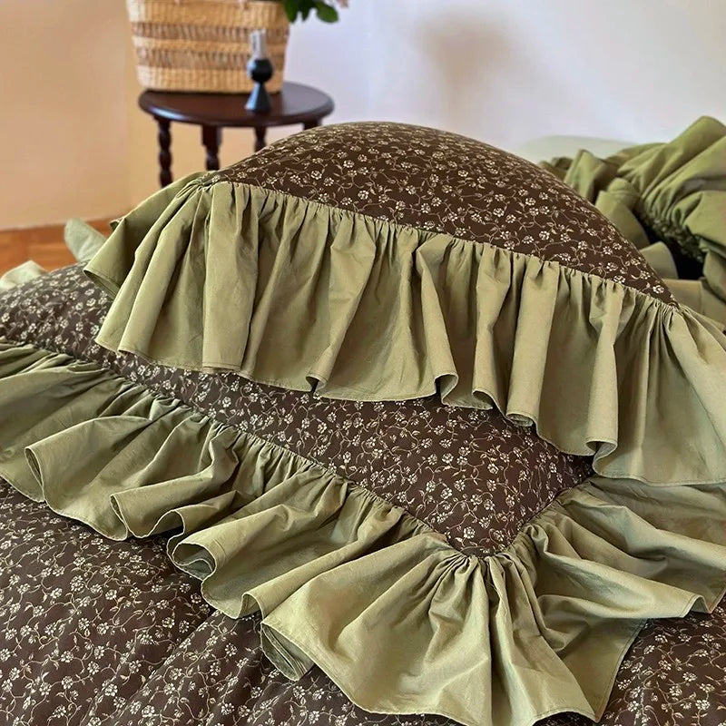 Close-up of layered olive green ruffles and coordinating floral pillow shams, MOSSBELLE – L&B