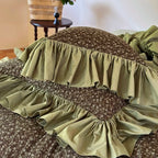 Close-up of layered olive green ruffles and coordinating floral pillow shams, MOSSBELLE – L&B
