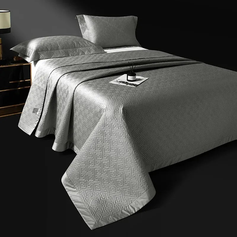 Pewter gray quilted bedspread layered over an abstract geometric jacquard duvet, LUSTRA PEWTER – L&B