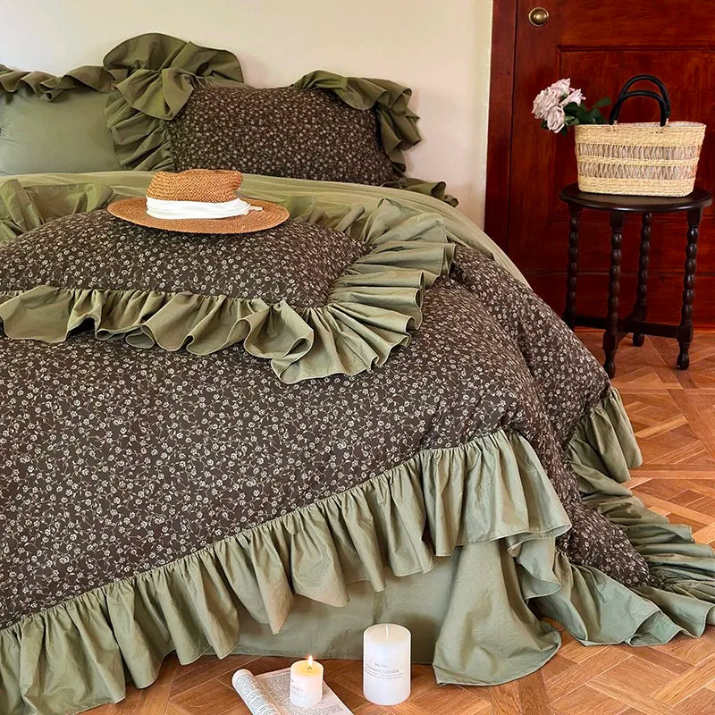 Olive green floral ruffle duvet cover with layered cottagecore styling, angled view of MOSSBELLE – L&B