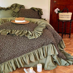 Olive green floral ruffle duvet cover with layered cottagecore styling, angled view of MOSSBELLE – L&B