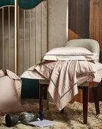 Champagne beige damask bedding draped over an accent chair to display its elegant jacquard pattern and satin finish - L&B