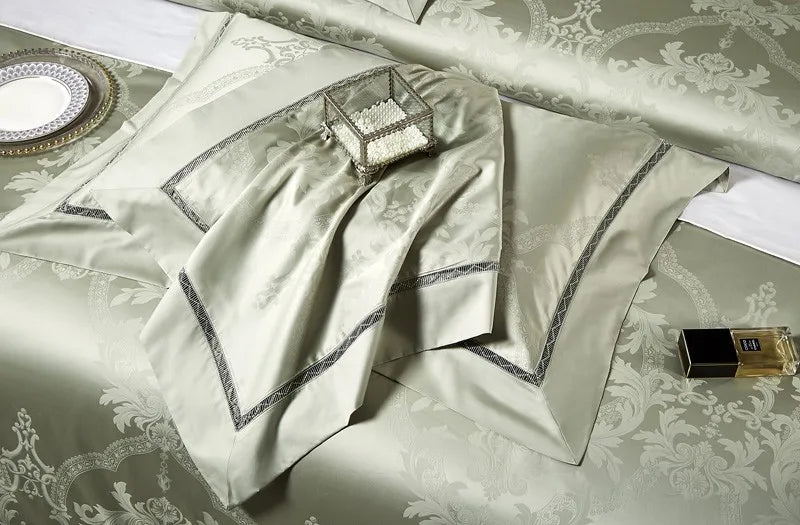 Folded sage green Egyptian cotton bedding with satin luster, couture-style bands, and detailed piping – L&B