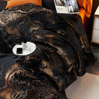 Detailed view of a black copper jacquard duvet cover with richly gathered folds and an ornamental metallic pattern – L&B