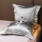 Silver jacquard pillow sham and folded duvet cover displayed with intricate metallic detailing and a soft gray finish – L&B