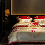 Romantic ivory floral bedding set with red embroidered accents, layered pillows, and an elegant satin sheen – L&B