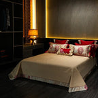 Thick quilted ivory bedspread styled with red floral embroidered pillows from the TROYAL bedding collection – L&B