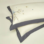 Coordinating ivory pillow shams with gray borders and delicate blue botanical embroidery – L&B