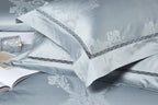 Coordinating sky blue pillow shams with damask detailing, braided trim, and a lustrous satin finish – L&B