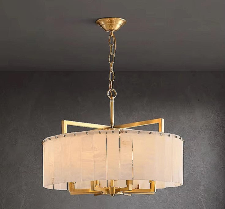 Round alabaster drum chandelier with gold chain suspension and warm ambient lighting